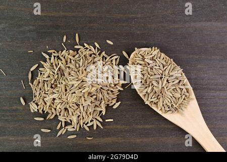 Tas de graines de cumin séchées sur fond en bois et dans une cuillère en bois Banque D'Images