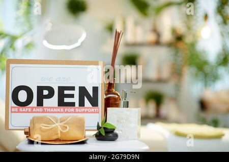 serviette, table de massage et panneau ouvert après le covid dans un studio de beauté moderne. Banque D'Images