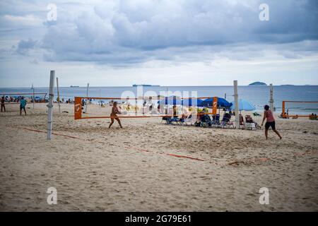 Un groupe de jeunes Brésiliens jouent au volley-ball au coucher du soleil à l'extrémité Leme de la plage de Copacabana. Banque D'Images