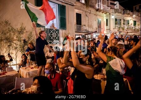 Tropea, Italie. 11 juillet 2021. Un homme vu portant un drapeau tandis que les gens se rendent compte que l'Italie avait gagné.parmi les restrictions Covid-19, les partisans italiens et étrangers regardent l'Italie contre l'Angleterre, l'Euro 2020 final match, dans les restaurants, les cafés et les bars à Tropea. La ville touristique de Calabre, sur la 'Côte des Dieuxs', avait été déclarée 'le plus beau hameau d'Italie' en 2021, pour son littoral emblématique. Crédit : SOPA Images Limited/Alamy Live News Banque D'Images