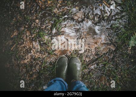 Les pieds de femme dans des bottes en caoutchouc le jour de la pluie. Banque D'Images