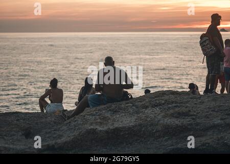 Un endroit magique: Les gens applaudissent quand le soleil se couche à Arpoador rocher avec vue sur la plage d'Ipanema et les montagnes de Morro Dois Irmaos et Leblon dans le dos. Appareil-photo: Leica M10 Banque D'Images