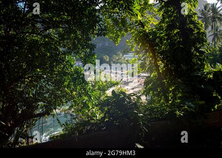 A pied de Praia Vermelha (plage Rouge), des eaux océaniques et des montagnes environnantes, à travers les arbres du sentier de Sugarloaf Mountain, situé à Rio de Janeiro, Brésil. Banque D'Images