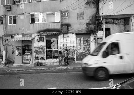 Une vue sur la rue qui donne sur une route avec des scooters et des graffitis sur le mur d'un bâtiment à Rocinha favela, une ville banale ou un bidonville à Rio, Brésil, Amérique du Sud Banque D'Images