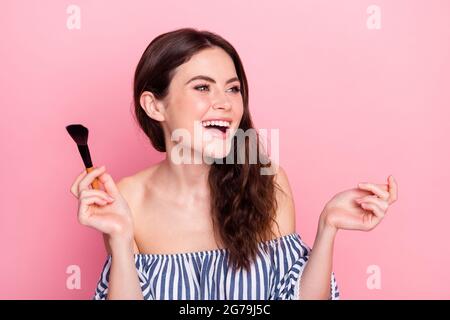 Photo de belle optimiste brune dame appliquer maquillage look vide espace porter robe bleue isolée sur fond rose couleur Banque D'Images