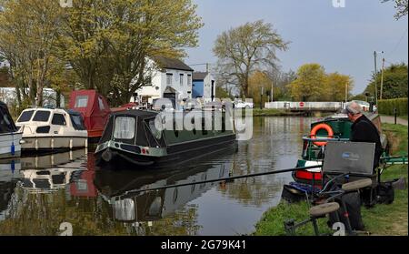 Le canal du pont tournant de Crabtree Lane sur le canal de Leeds et Liverpool est de plus en plus occupé alors qu'un bateau étroit sur le canal passe devant un regard de pêcheur. Banque D'Images