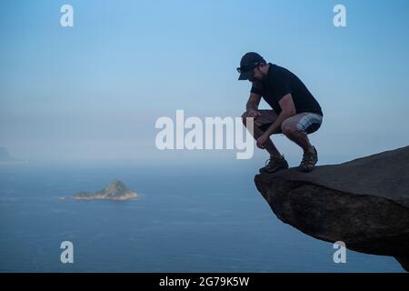 Un homme qui profite de la vue sur les plages sauvages depuis un rocher au sommet de la montagne Pedra do Telegrafo, Barra de Guaratiba, Rio de Janeiro, Brésil. Prise de vue avec Leica M10 Banque D'Images