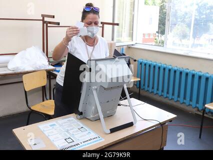 Les personnes ayant un masque utilisent un système de vote lors des élections législatives bulgares à Sofia, en Bulgarie, le 11 juillet 2021 Banque D'Images