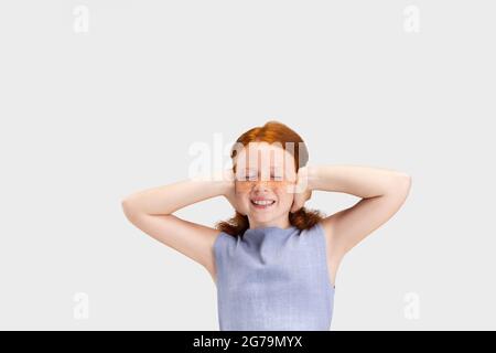 Portrait d'une jolie fille à tête rouge à revers dans un ensemble décontracté posé isolé sur fond blanc de studio. Concept d'enfance heureuse. Enfant ensoleillé Banque D'Images