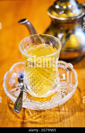 Thé libanais dans une tasse de verre placée sur la table avec une théière floue à l'arrière-plan Banque D'Images