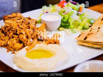 Poulet mariné grillé au houmous, pain Pitta et salade. Authentique cuisine du Moyen-Orient du restaurant. Banque D'Images