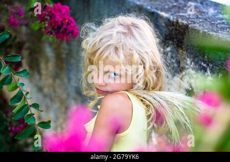 belle petite fille blonde et fleurs roses Banque D'Images