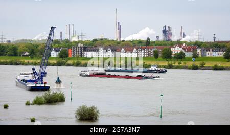 Duisburg, Rhénanie-du-Nord-Westphalie, Allemagne - paysage urbain dans la région de la Ruhr avec des navires de cargaison sur le Rhin devant des bâtiments résidentiels dans le district de Laar et dans le haut-fourneau arrière 8 de ThyssenKrupp Huettenwerk à Bruckhausen, en front navire grue rêve le Rhin. Banque D'Images