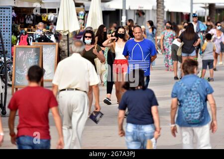 Vendrell, Espagne. 11 juillet 2021. Les gens avec des masques de visage et d'autres sans masques de visage marchent le long de Paseo Maritimo Street à Vendrell.depuis le 26 juin dernier, En Espagne, il n'est plus obligatoire d'utiliser un masque facial pour éviter la contagion de Covi-19 dans les espaces extérieurs tant que la distance de 1.5 mètres entre les gens est respectée. Il y a encore des gens qui le portent volontairement comme mesure de protection. Crédit : SOPA Images Limited/Alamy Live News Banque D'Images