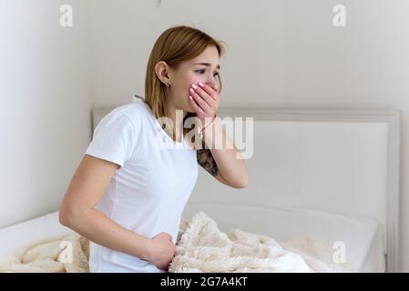 La jeune femme se sent nauséabonde sur le lit. Vomissez bientôt. Empoisonnement, problèmes d'estomac. Banque D'Images