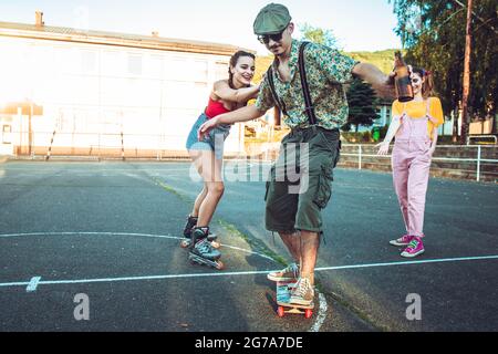 Un jeune garçon sur le skate avec deux filles derrière lui acclamations et rire Banque D'Images