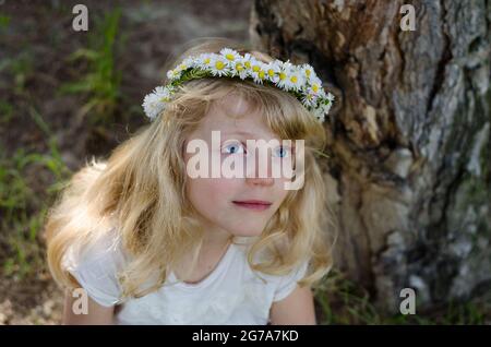 adorable petite fille blonde souriante avec serre-tête à fleurs Banque D'Images