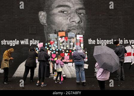 Les gens placent des messages de soutien au-dessus des sacs de poubelle qui ont été placés sur des mots offensants sur la fresque de l'attaquant de Manchester United et du joueur d'Angleterre Marcus Rashford sur le mur du café Coffee House sur Copson Street, Withington, Qui semblait vandalisé le matin après que l'équipe de football d'Angleterre a perdu la finale de l'UEFA Euro 2021. Date de la photo: Lundi 12 juillet 2021. Banque D'Images