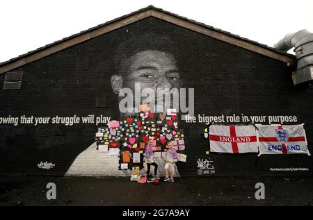 Ruby Swave, 7 ans (à gauche) et sa sœur Reeva Swave, 4 ans, placent des messages de soutien au-dessus des sacs poubelle qui ont été placés sur des mots offensifs sur la fresque de l'attaquant de Manchester United et du joueur d'Angleterre Marcus Rashford sur le mur du café Coffee House sur Copson Street, Withington, Qui semblait vandalisé le matin après que l'équipe de football d'Angleterre a perdu la finale de l'UEFA Euro 2021. Date de la photo: Lundi 12 juillet 2021. Banque D'Images