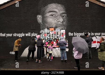 Les gens placent des messages de soutien au-dessus des sacs de poubelle qui ont été placés sur des mots offensants sur la fresque de l'attaquant de Manchester United et du joueur d'Angleterre Marcus Rashford sur le mur du café Coffee House sur Copson Street, Withington, Qui semblait vandalisé le matin après que l'équipe de football d'Angleterre a perdu la finale de l'UEFA Euro 2021. Date de la photo: Lundi 12 juillet 2021. Banque D'Images