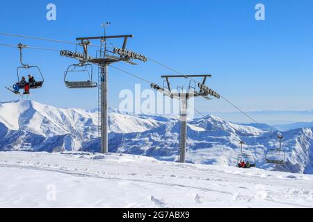 Géorgie, Gudauri, 8 mars 2013 : supports de téléphérique avec chaises et skieurs. Sur fond de neige et de ciel bleu. Le concept d'actif Banque D'Images