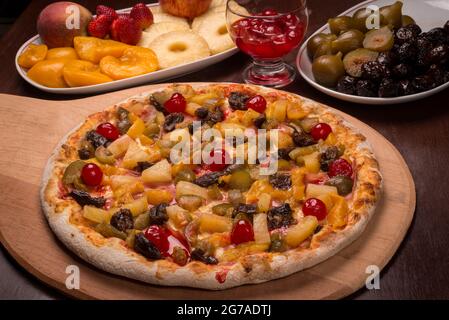 Pizza à la pêche, la cerise, la prune, la figue et l'ananas sur une planche de bois. Pizza sucrée brésilienne. Banque D'Images