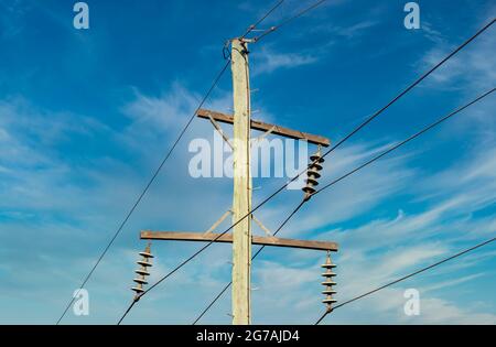 Photographie d'un poste téléphonique en bois et de câbles contre un ciel bleu Banque D'Images