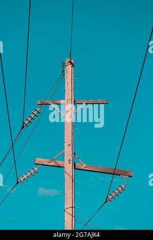 Photographie d'un poste téléphonique en bois et de câbles contre un ciel bleu Banque D'Images