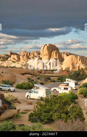 Les RVS dans un camping au milieu d'énormes rochers au parc national de Joshua Tree par une journée ensoleillée Banque D'Images