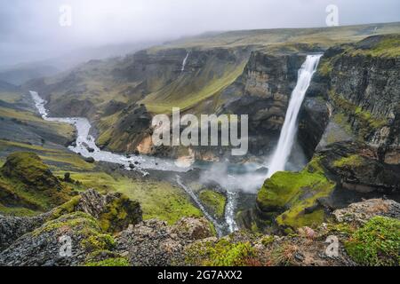 Highlands d'Islande. Cascade de Haifoss et rivière Fossa dans la vallée. Les collines et les falaises sont couvertes de mousse verte. Banque D'Images