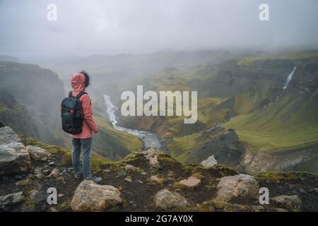 Femme avec sac à dos sur le point de vue sur la fosse de la rivière près de la cascade de Haifoss. Islande Highland Banque D'Images