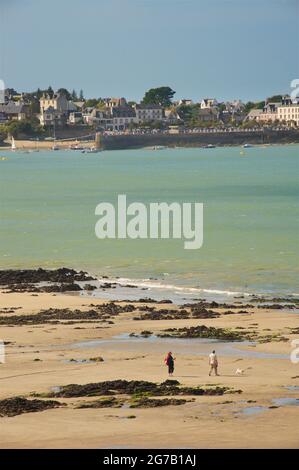 Vue sur l'immense plage de sable de Locquirec à marée basse, Bretagne, France. Couple marchant un chien Banque D'Images