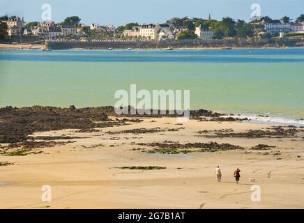 Vue sur l'immense plage de sable de Locquirec à marée basse, Bretagne, France. Couple marchant un chien Banque D'Images