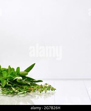 Bouquet d'herbes épicées partiellement sur une surface blanche avec réflexion. Banque D'Images