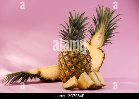 Ananas frais mûr et tranches de fruits coupées sur fond rose. Promotion Hello, Summer ou Summer Season. Banque D'Images