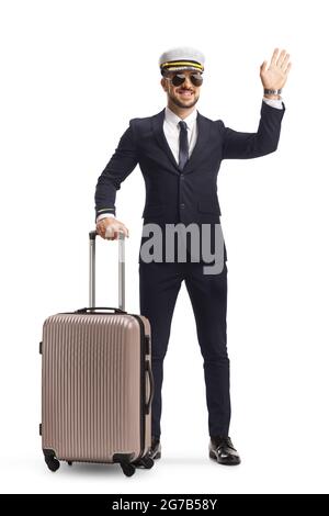 Portrait complet d'un jeune pilote avec une valise agitant à la caméra isolée sur fond blanc Banque D'Images