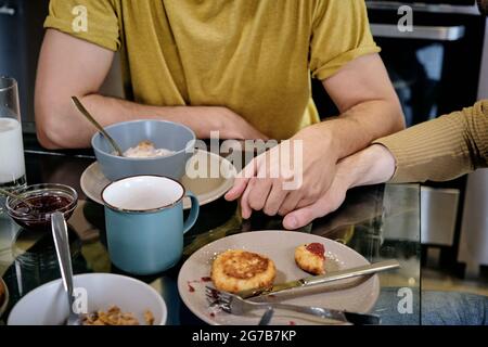 Deux hommes tiennent la main lorsque vous mangez le petit déjeuner ensemble à la maison Banque D'Images