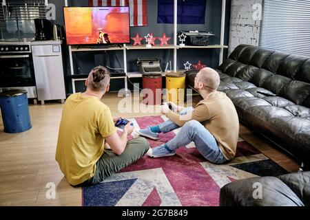 Des amis qui jouent ensemble au jeu vidéo lorsqu'ils sont assis sur le sol du salon Banque D'Images