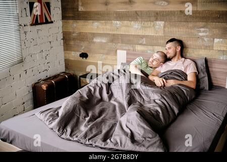 Des jeunes gais heureux se détendent et se coudent dans un lit sous une couverture le matin Banque D'Images