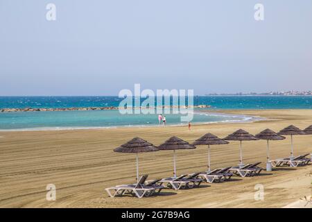 Chaises longues, parasols en paille, plage vide, Robinson Club Cyprus, Alaminos, Chypre Banque D'Images