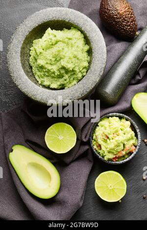 Mortier avec guacamole savoureux, avocat et lime sur fond sombre Banque D'Images