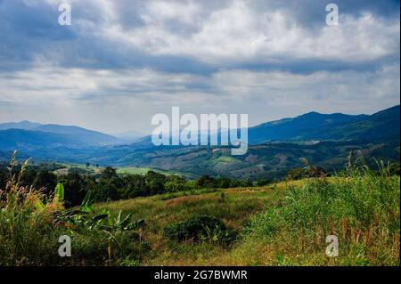 Montagnes collines avec de nombreux champs agricoles entourés par la nature avec ciel nuageux Banque D'Images