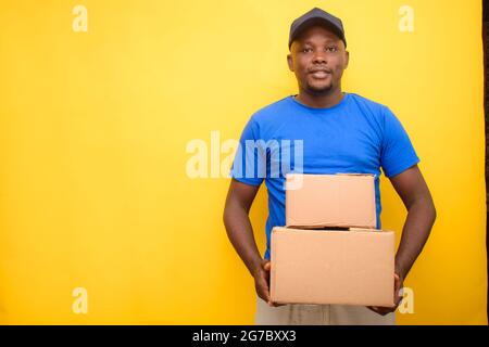 Un homme de livraison ou d'expédition africain transportant des boîtes et portant une casquette Banque D'Images