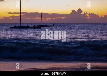 Deux voiliers amarrés dans les Caraïbes au large de la rive près de Frederiksted, Sainte Croix, USVI comme le coucher du soleil se reflète dans les nuages et la mer. Banque D'Images