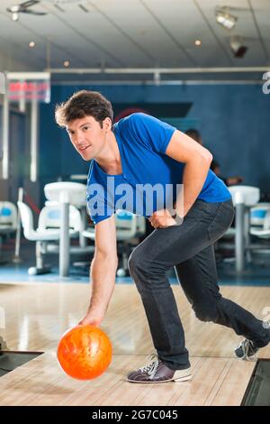 Jeune homme de bowling s'amuser, l'homme sportif jouer a bowling ball en face de l'tenpin alley Banque D'Images