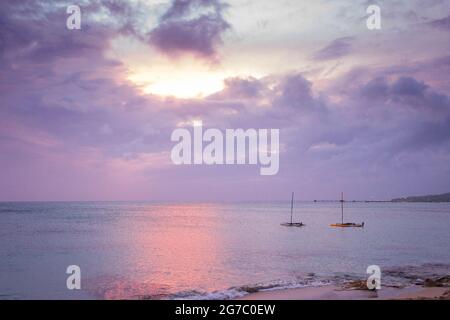 Deux voiliers amarrés dans les Caraïbes au large de la rive près de Frederiksted, Sainte Croix, USVI comme le coucher du soleil se reflète dans les nuages et la mer. Banque D'Images