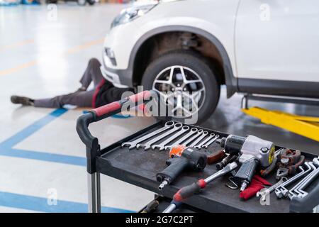 Sélectionner l'équipement de mise au point du mécanicien de voiture qui règle la tension de l'élément de suspension du véhicule au centre de réparation automobile, concept de suspension de voiture Banque D'Images