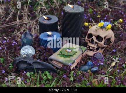 Encore la vie avec les objets rituels Beltane, le crâne, les bougies brûlantes, les cristaux et le livre magique des sorts. Arrière-plan ésotérique, gothique et occulte, Halloween M. Banque D'Images
