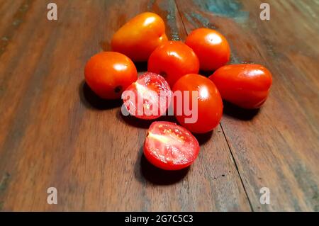 Malang, Indonésie - 11 juillet 2021 : QUELQUES TOMATES FRAÎCHES et quelques tranches sur une planche de bois Banque D'Images