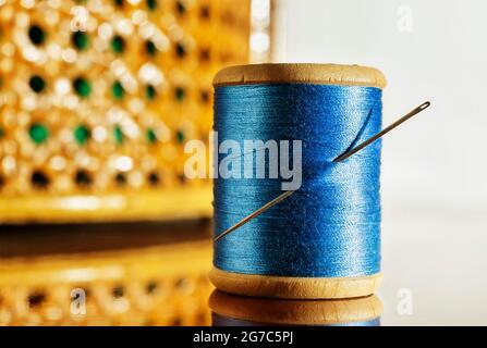 Bobine de fil bleu et une aiguille sur table en bois, dans le panier à coudre de fond Banque D'Images